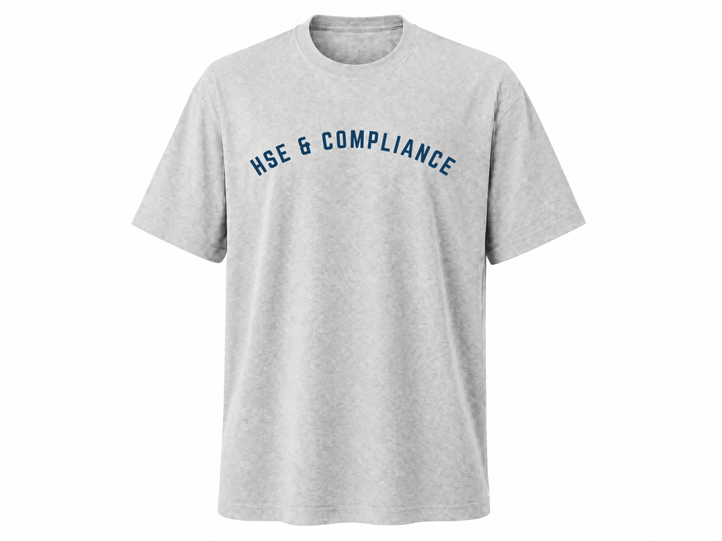 A light heather gray crewneck t-shirt with the words 'HSE & COMPLIANCE' printed in navy blue arched text across the chest, displayed on a clean white background.