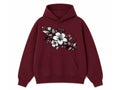 A maroon pullover hoodie with a white and black floral graphic printed on the chest, displayed against a solid white background.